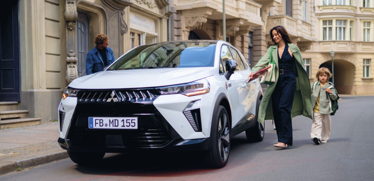 Eine Vierk&ouml;pfige Familie l&auml;uft auf den parkenden Grandis zu.