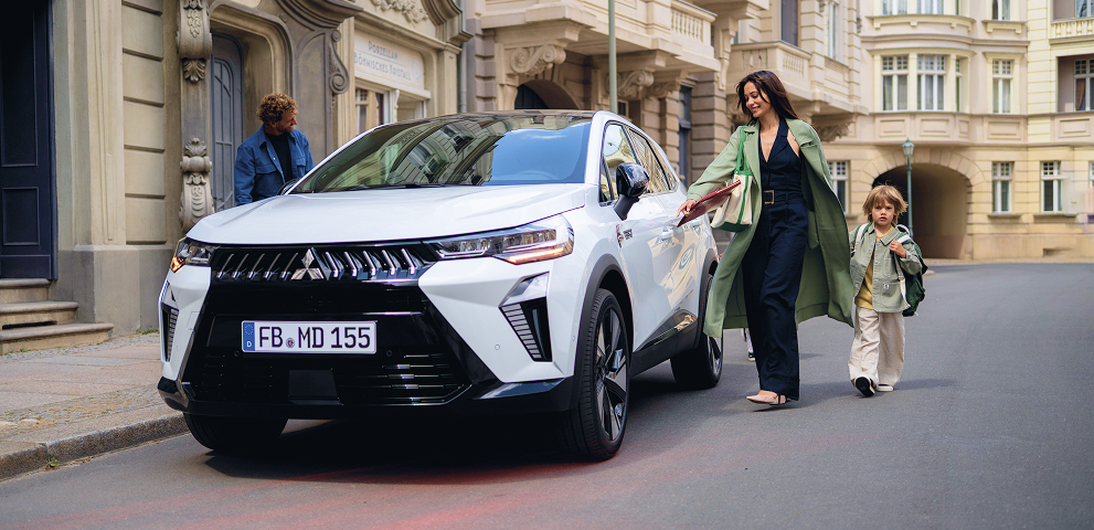 Eine Vierk&ouml;pfige Familie l&auml;uft auf den parkenden Grandis zu.