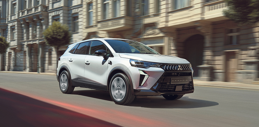 Ein wei&szlig;er Mitsubishi Grandis f&auml;hrt durch die Stadt.