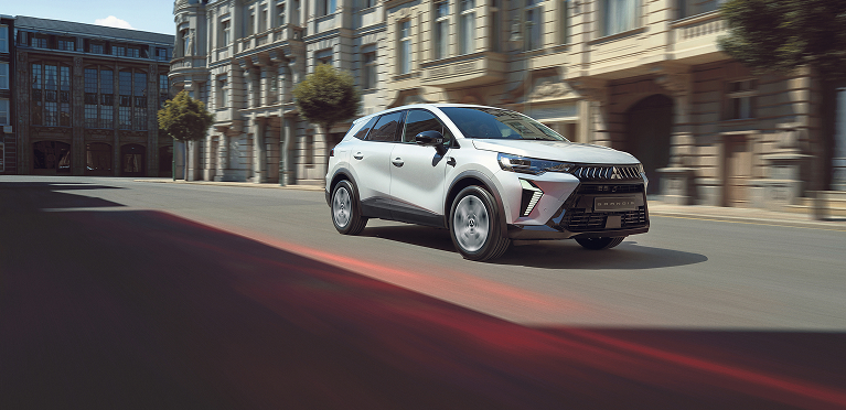 Ein wei&szlig;er Mitsubishi Grandis f&auml;hrt durch die Stadt.