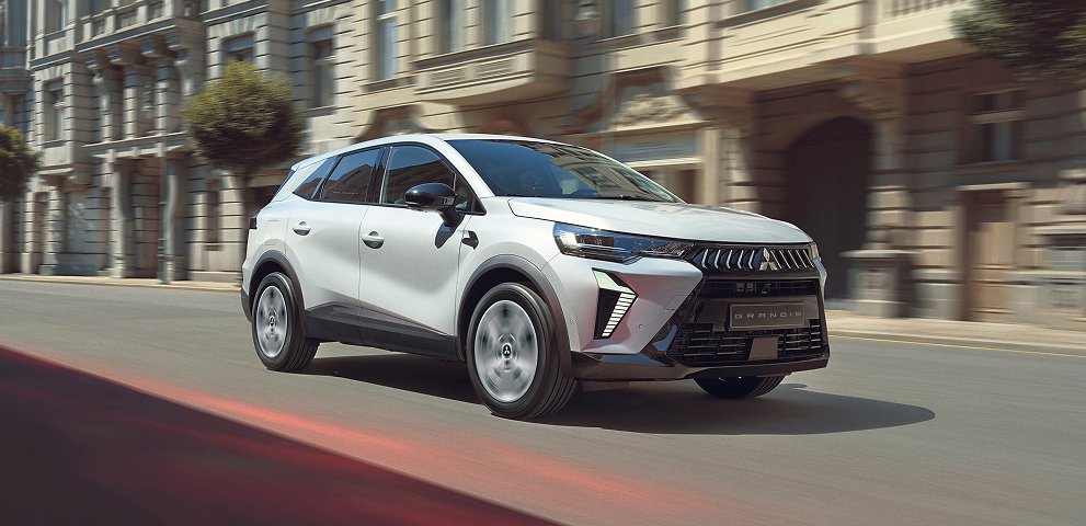 Ein wei&szlig;er Mitsubishi Grandis f&auml;hrt durch die Stadt.