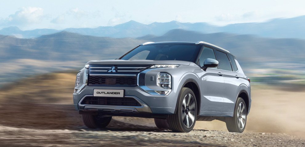 Ein grauer Mitsubishi Outlander f&auml;hrt durchs Gel&auml;nde.