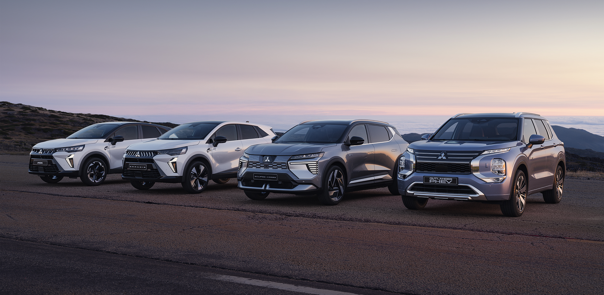 Die Mitsubishi ASX, Grandis, Eclipse Cross und Outlander stehen in der D&auml;mmerung am Stra&szlig;enrand.