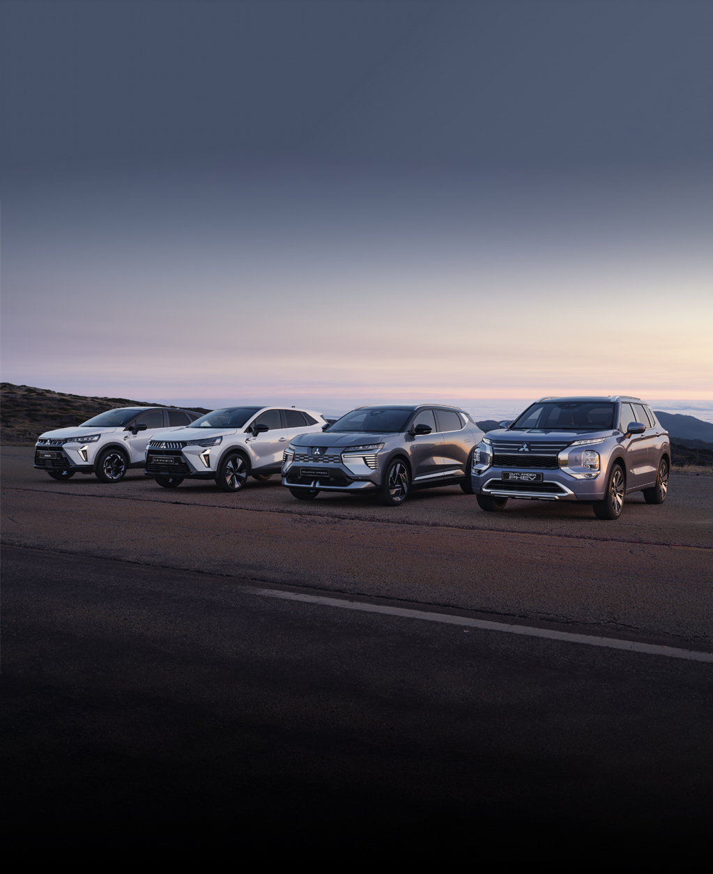 Die Mitsubishi ASX, Grandis, Eclipse Cross und Outlander stehen in der D&auml;mmerung am Stra&szlig;enrand.