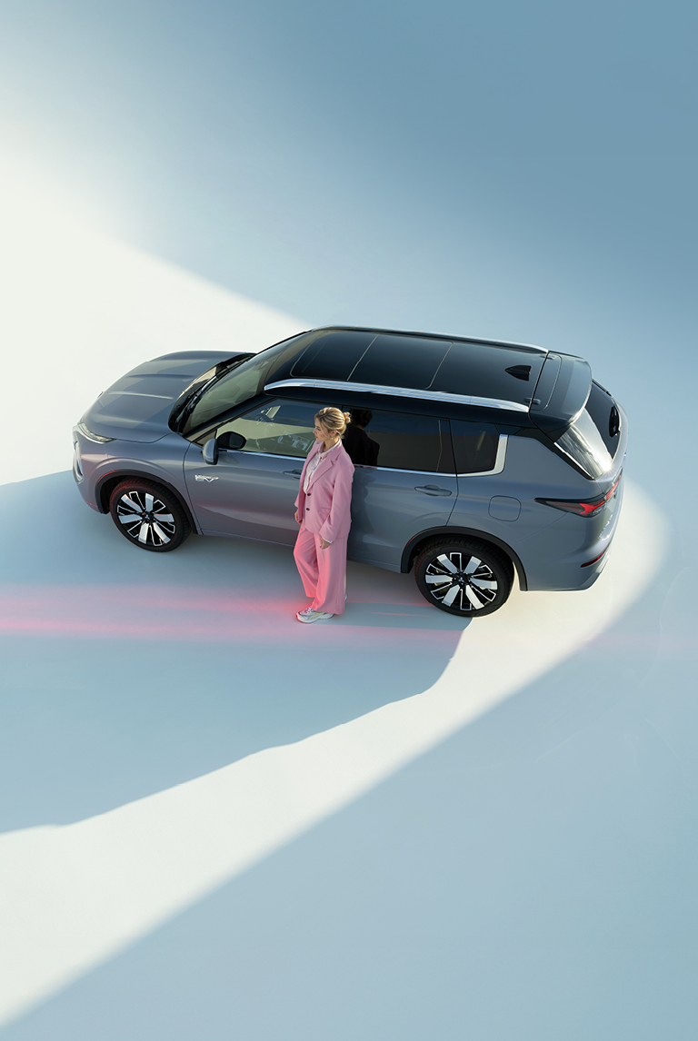 Frau lehnt an der Fahrert&uuml;r des Outlanders