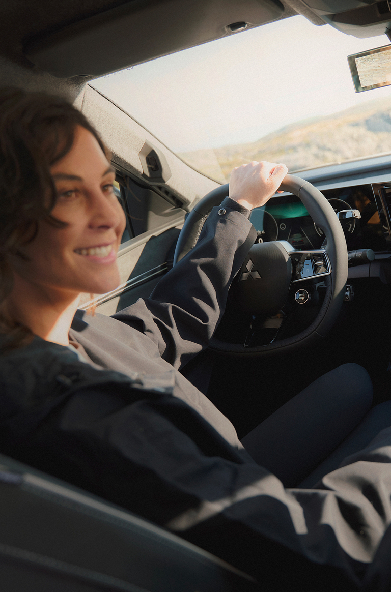 Eine Frau schaut auf dem Fahrersitz sitzend zu ihrem m&auml;nnlichen Beifahrer, auf dem Infotainment erkennt man die Fahreinstellung ECO.