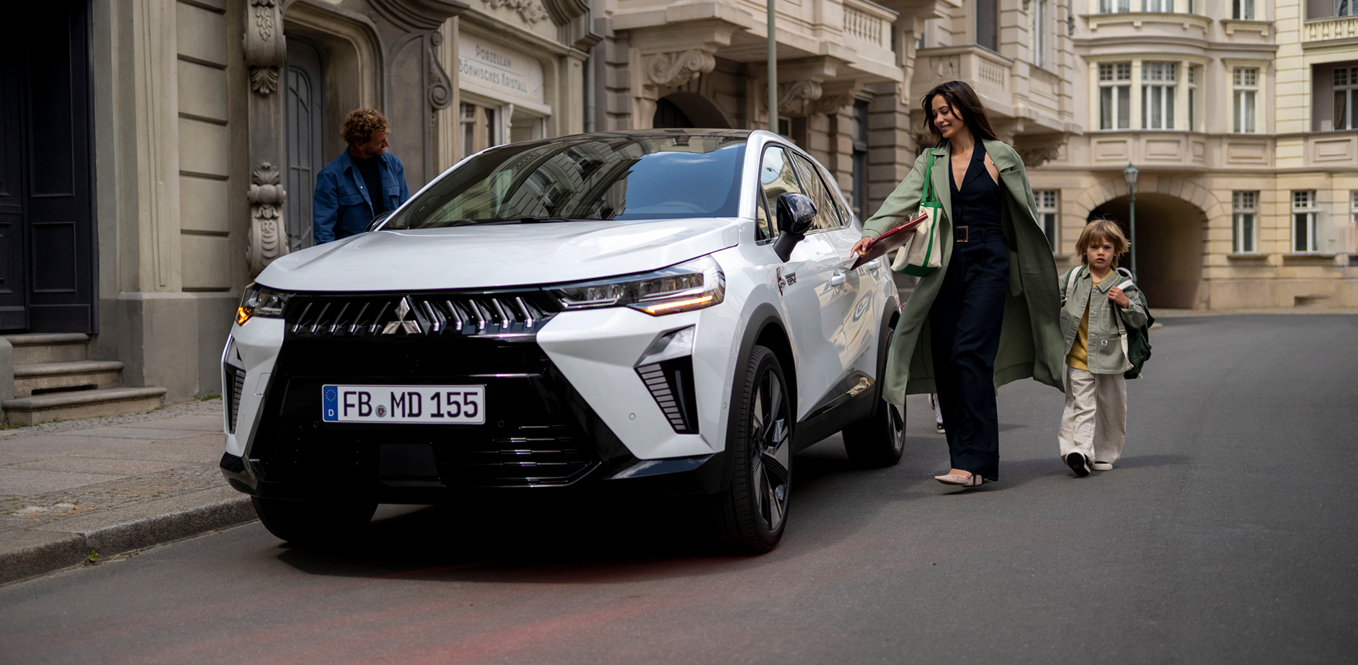 Frau mit Kind an der Hand l&auml;uft auf den parkenden Grandis zu