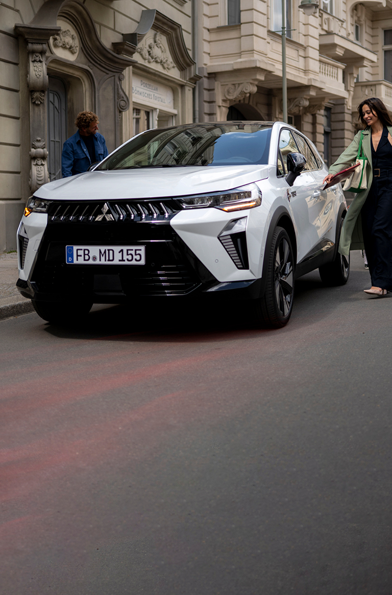 Frau mit Kind an der Hand l&auml;uft auf den parkenden Grandis zu