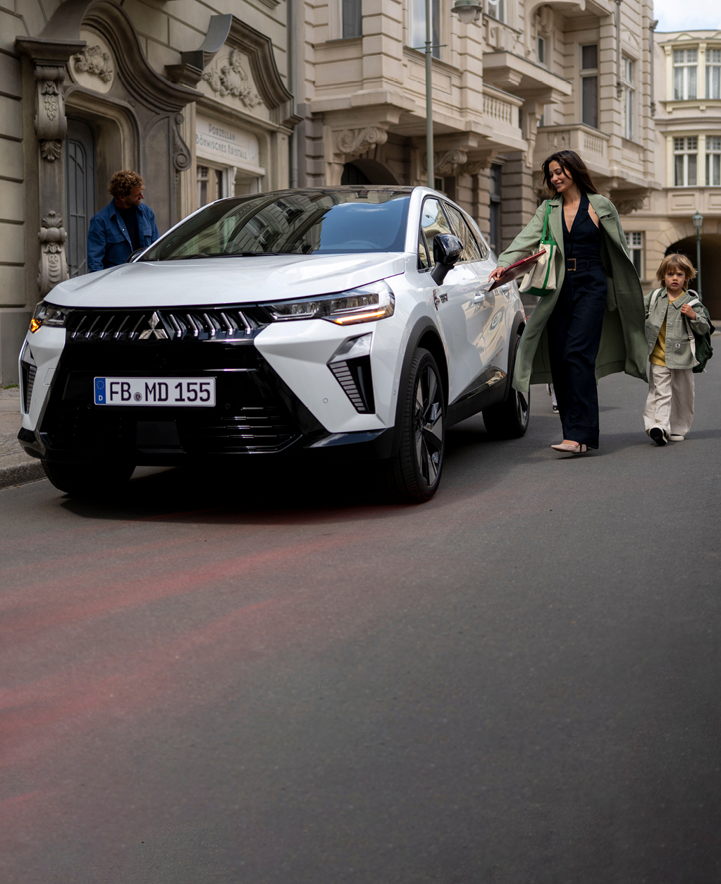 Frau mit Kind an der Hand l&auml;uft auf den parkenden Grandis zu