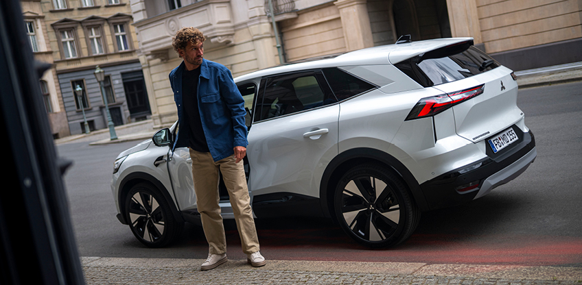 Ein Mann steht neben dem parkenden Grandis am Stra&szlig;enrand