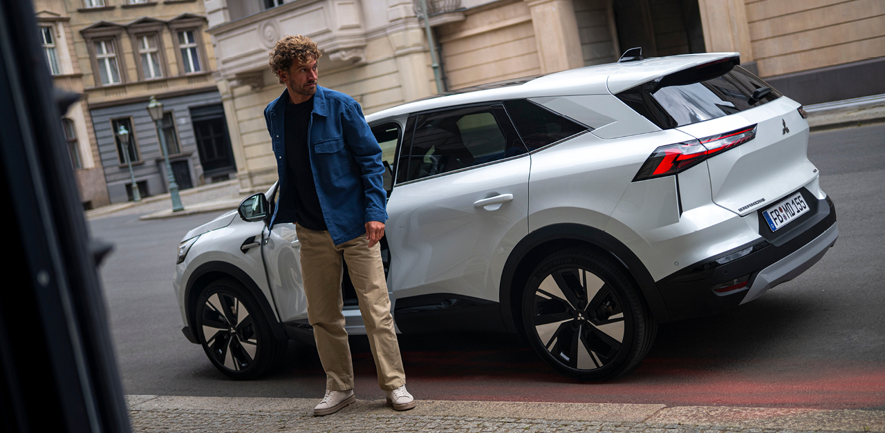 Ein Mann steht neben dem parkenden Grandis am Stra&szlig;enrand