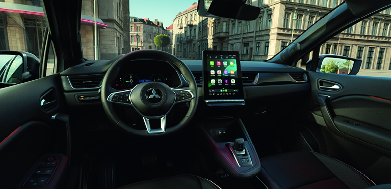 Modernen Innenraum eines Mitsubishi Grandis mit Multifunktionslenkrad, digitalem Cockpit und gro&szlig;em zentralen Touchscreen mit Apps, Blick nach au&szlig;en in eine Stadt.