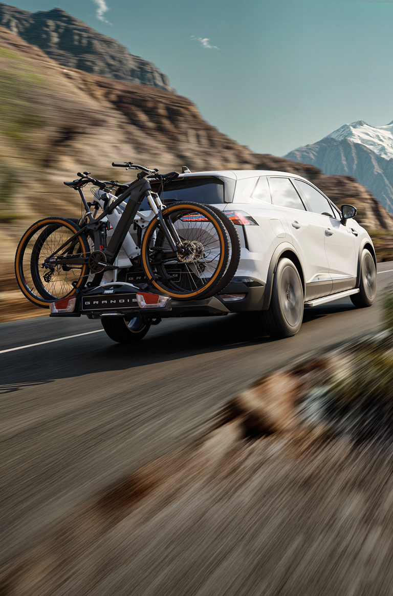 Der Mitsubishi Grandis mit Fahrrad-Hecktr&auml;ger beladen mit 2 Fahrr&auml;dern f&auml;hrt eine Gebirgsstra&szlig;e entlang.