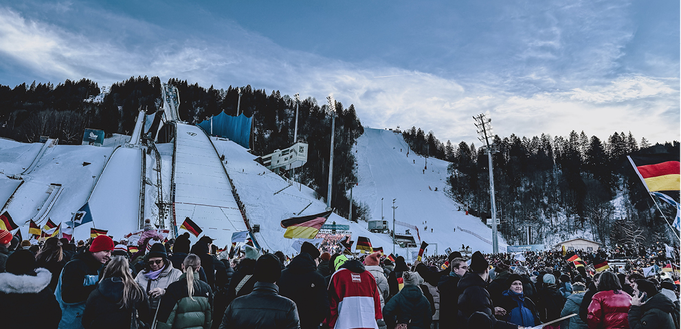 Ein Skispringer mit daneben abgebildetem Logo von der Vierschanzentournee und Mitsubishi.